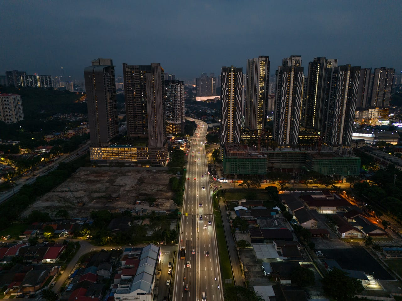 Old Klang Road night aerial — highway light trails and Kuala Lumpur skyline near M Aurora