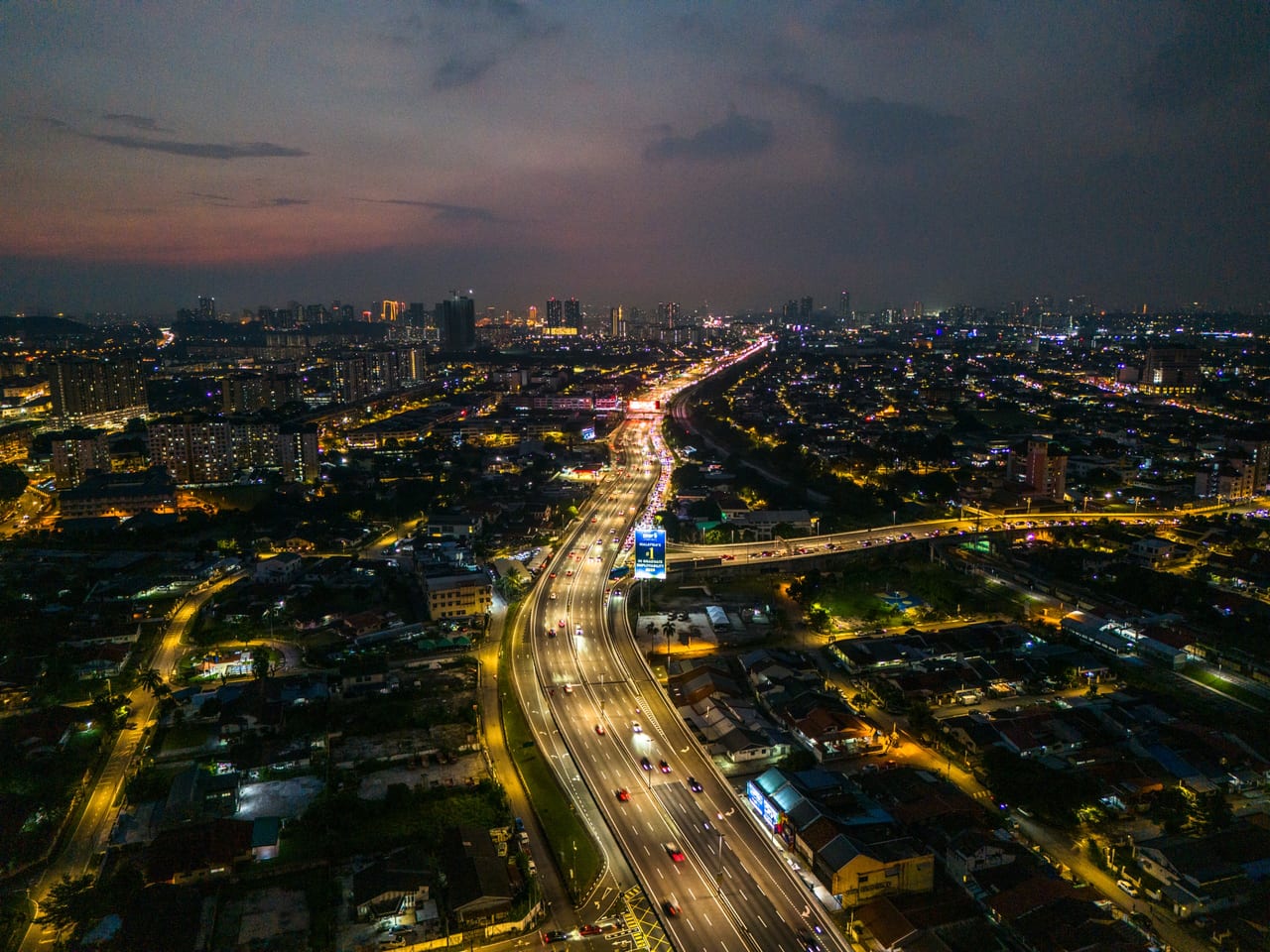 Old Klang Road sunset aerial — highway interchange and KL skyline near M Aurora
